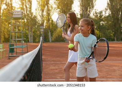 Mother with her daughter playing tennis on court - Powered by Shutterstock