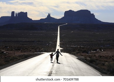 Mother And Her Daughter Are Running On US 163, Near Forrest Gump Point, Monument Valley.