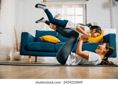 A mother and her daughter share a playful family yoga moment playfully imagining themselves as airplanes in the air building trust harmony and lasting happiness in their lives together. - Powered by Shutterstock