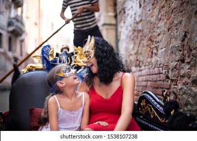 A mother and her daughter wears Venetian masks and traveling with gondola at the canals  of Venice, Italy . Venice mask festival at the canal with gondola .
