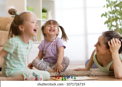 Mother And Her Kids Daughters Playing In Board Game