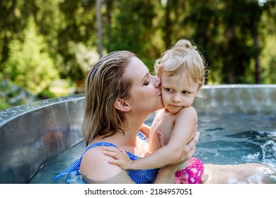 Mother With Her Little Daughter Enjoying Bathing In Wooden Barrel Hot Tub, Summer Vacation Concept.