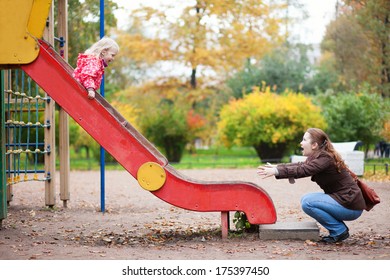 Mother and her little daughter are having fun together at the playground
