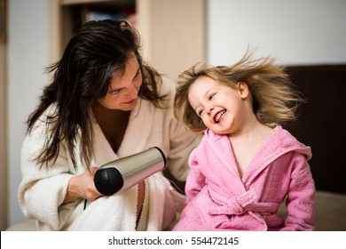 Mother and her little daughter having fun with hairdryer - Powered by Shutterstock