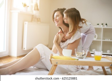 Mother with her little daughter having breakfast in the bed. Mother and her daughter enjoying a healthy breakfast together. - Powered by Shutterstock