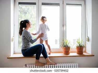 Mother with her little daughter looking out of window