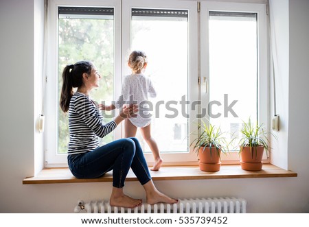 Mother with her little daughter looking out of window