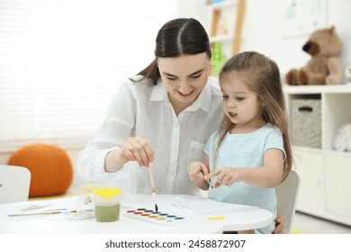 Mother and her little daughter painting with watercolor at home - Powered by Shutterstock