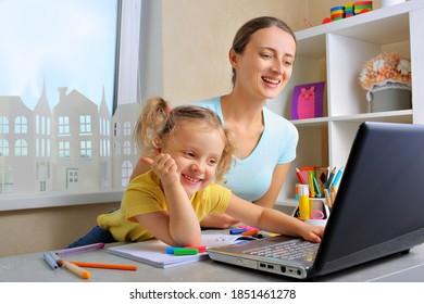 Mother And Her Little Daughter Sit At The Kitchen Table Studying Online Together. Mom And Little Girl Draw, Study At Home, Remote Learning Concept