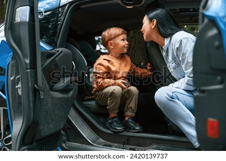 Mother with her little son are in the modern car, having fun.