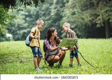 Mother And Her Little Sons Hiking .They Taking A Break And Examining Map.	