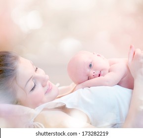 Mother And Her Newborn Baby. Happy Mother And Baby Kissing And Hugging. Resting In Bed Together. High Key Soft Image Of Beautiful Family. Maternity Concept. Parenthood. Motherhood 