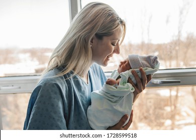 A Mother with her newborn baby at the hospital in front of a window
