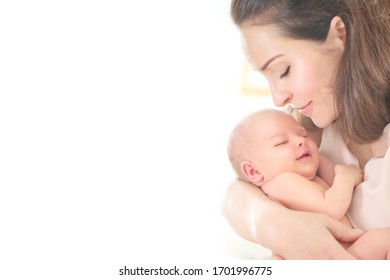 Mother and her Newborn Baby together. Love. Happy Mother and Baby kissing and hugging. High key soft image of Beautiful Family. Maternity concept. Parenthood. Motherhood, adoption concept