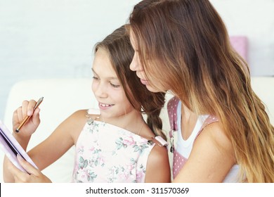 Mother With Her Preteen Daughter Playing Ipad Together