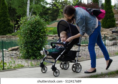 Mother with her small baby bo are walking in the park