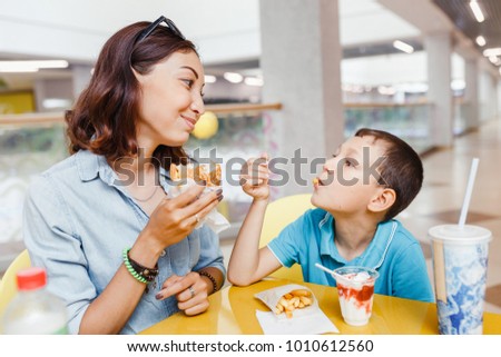 Mother And her son eating a fast food hamburher Together At The Mall
