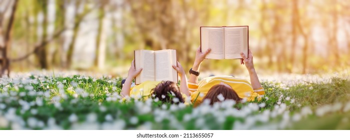 Mother and her son lying down on the beautiful spring field in the sunny park. Concept of the interesting of literature and family leisure. - Shutterstock ID 2113655057