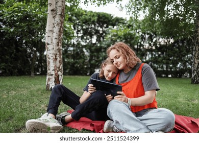 Mother and her son using tablet in summer park - Powered by Shutterstock