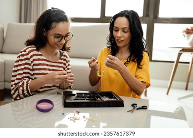 A mother and her teenage daughter engaged in making bead jewelry at home - Powered by Shutterstock