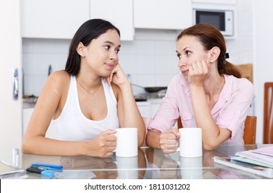 Mother And Her Teenage Daughter Talking At Kitchen Table