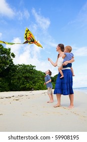 Mother And Her Two Kids Flying Kite On White Sand Tropical Beach