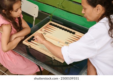 A mother and her young daughter enjoying a game of backgammon at home. Family bonding and quality time together. - Powered by Shutterstock