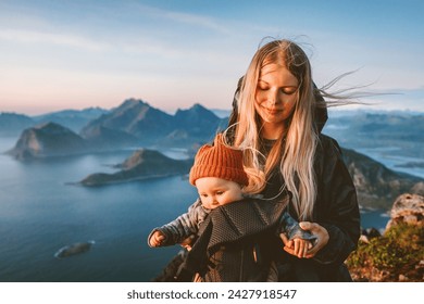 Mother hiking with baby carrier healthy lifestyle outdoor family time travel in Norway summer vacations scandinavian woman with child in mountains of Lofoten islands aerial view - Powered by Shutterstock