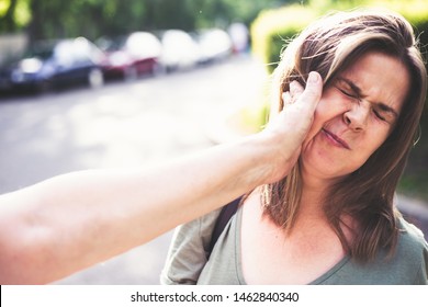 Mother hitting daughter on the street in daylight – Parent abuse outdoor in public – Hand slapping a teen’s face – Concept of awareness raised against aggressive bully parents