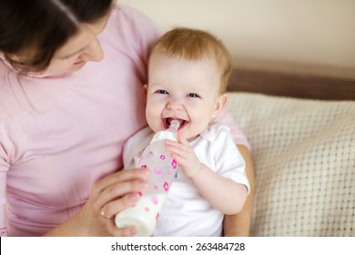 Mother Holding A Baby And Feeds With A Baby Bottle 