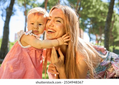 Mother holding baby girl close, both smiling brightly in a sunlit park, capturing a loving moment - Powered by Shutterstock