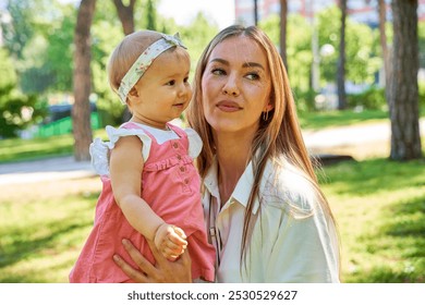 Mother holding baby girl outdoors in the park. - Powered by Shutterstock