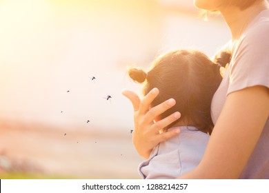 Mother holding baby girl in the park.Little girl has allergies with mosquitoes bite.Mother protection kid.Mosquito blood breeding on kids.Repellent, Dengue virus, Yellow fever, West nile, Malaria.