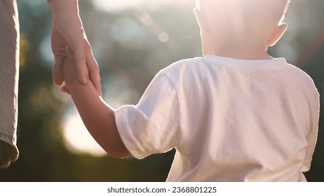 mother holding baby hand close-up. happy family father's day kid dream concept. close-up hands mom and son kid holding hands outdoors in park. mother takes care of lifestyle baby holds hand - Powered by Shutterstock