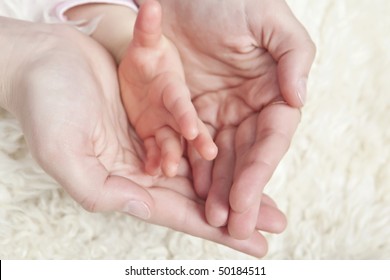 Mother holding baby hand in her hands