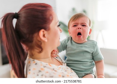 A mother holding child baby on the living room. The baby is sick having some cough