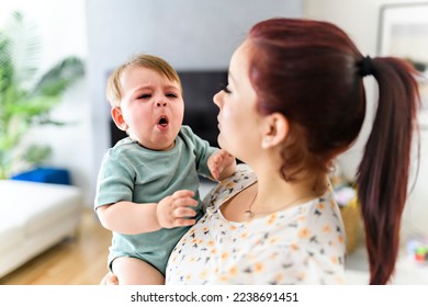 A mother holding child baby on the living room. The baby is sick having some cough - Powered by Shutterstock