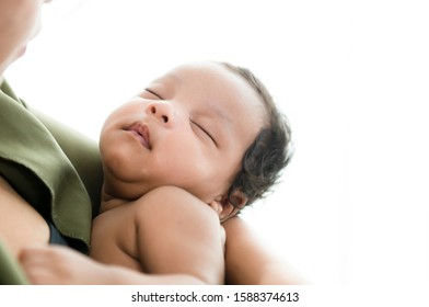 Mother holding cute little kid daughter sleeping on her arms a charming sleeping little boy.Happy black mom hug small mixed race child caring after breastfeeding