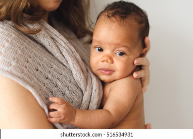 Mother Holding Cute Newborn Smiling Child. Adorable African Baby Looking At Camera On Mom Hands