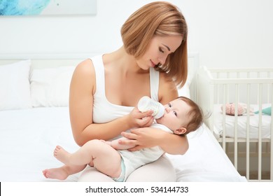 Mother Holding And Feeding Baby From Bottle