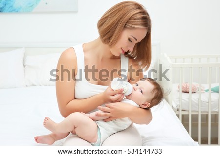 Mother holding and feeding baby from bottle