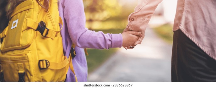 Mother holding the hand of a daughter and escorting her to school. - Shutterstock ID 2336623867