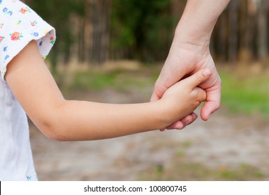 Mother holding a hand of her daughter  in spring day outdoors