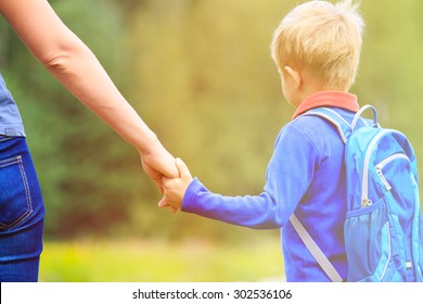 Mother Holding Hand Of Little Son With Backpack Outdoors, Back To School