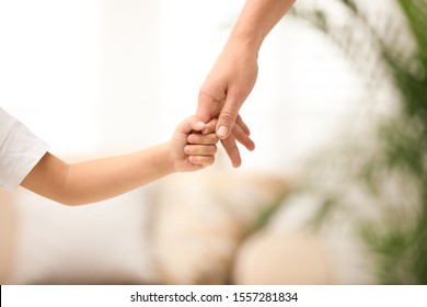 Mother holding hands with her child indoors, closeup. Happy family - Powered by Shutterstock