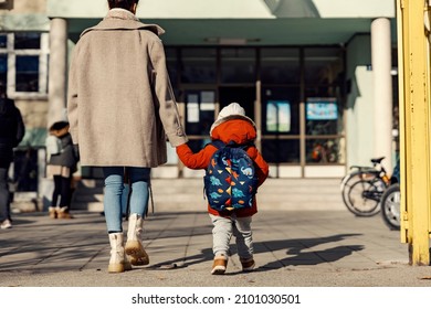 A mother holding hands with her little son and entering the kindergarten yard. - Shutterstock ID 2101030501