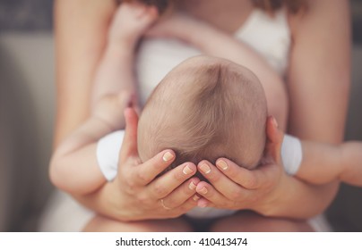 Mother Holding Head Of Her Newborn Son In Hands. The Baby On Hands At Mum. Loving Mother Hand Holding Cute Sleeping Newborn Baby Child