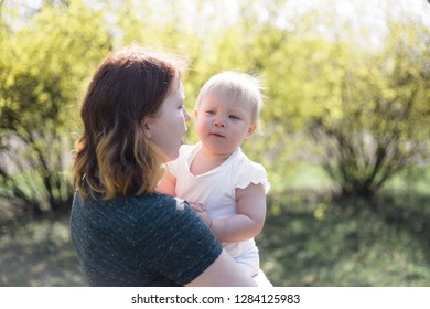 Mother Holding Her Baby Daughter On A Sunny Spring Day. High Key Lifestyle Image, Shallow Depth Of Field.