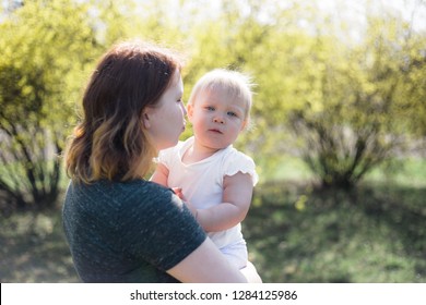 Mother Holding Her Baby Daughter On A Sunny Spring Day. High Key Lifestyle Image, Shallow Depth Of Field.