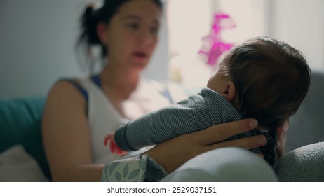 Mother holding her baby, focusing on their interaction in a cozy, sunlit room. tender moment, capturing the bond between mother and child - Powered by Shutterstock